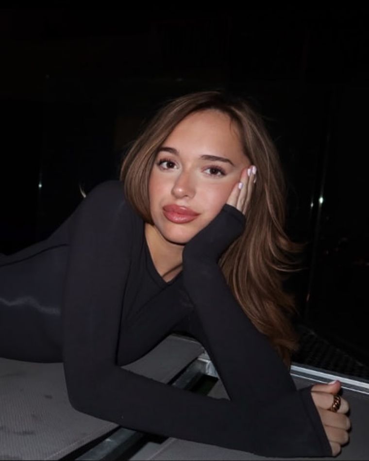 Creator in a black bodysuit posing poolside at night